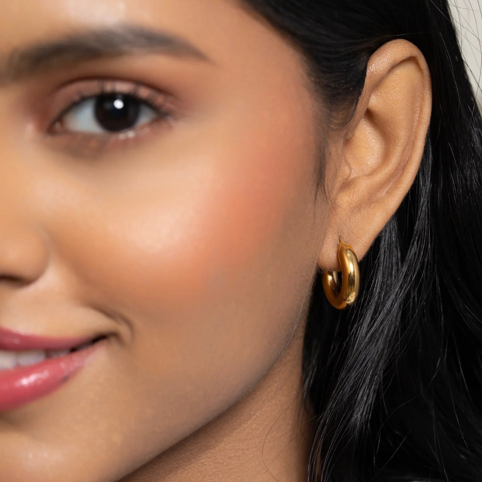 Close-up of a woman wearing a gold hoop earring.