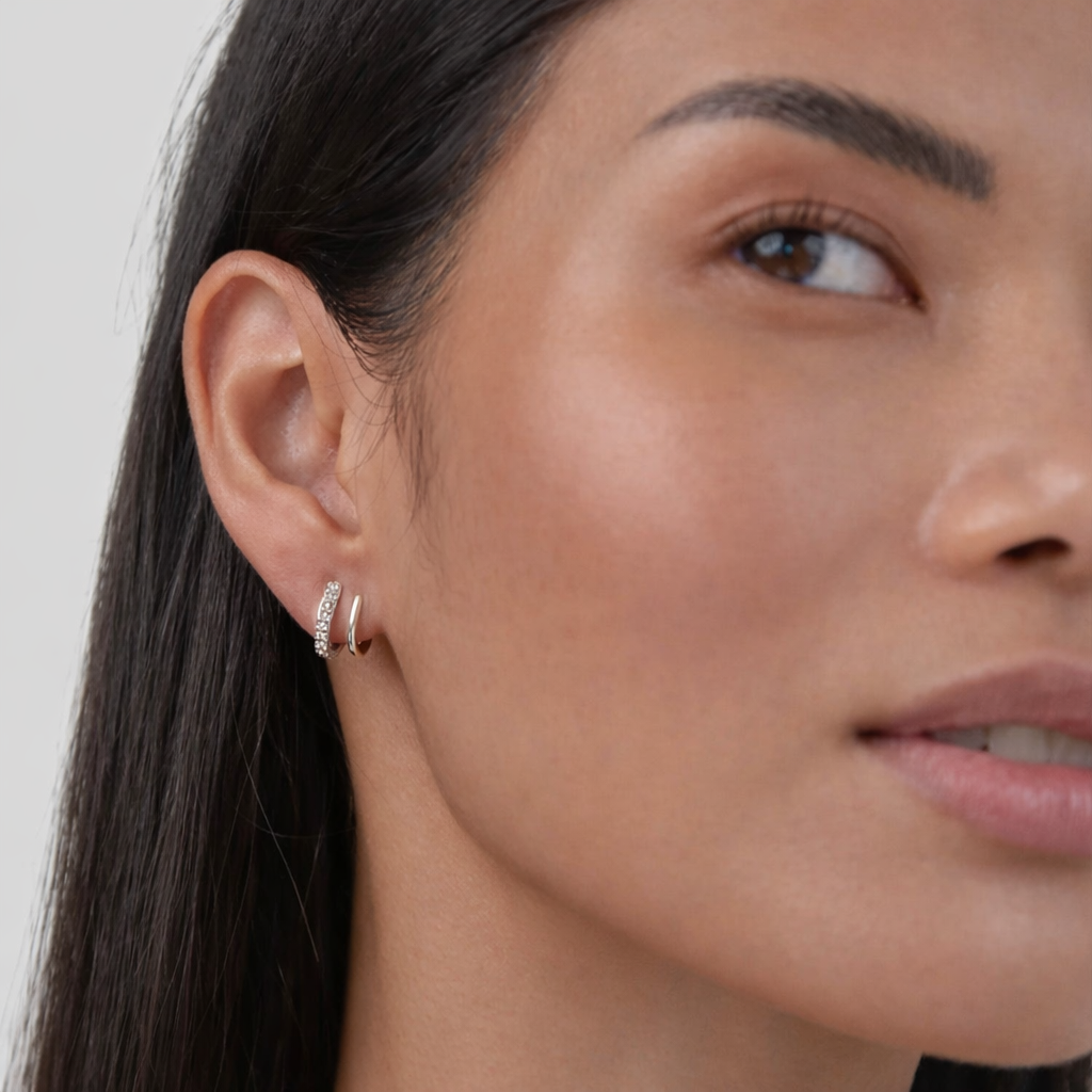 Close-up of a woman wearing a silver hoop earring against a neutral background