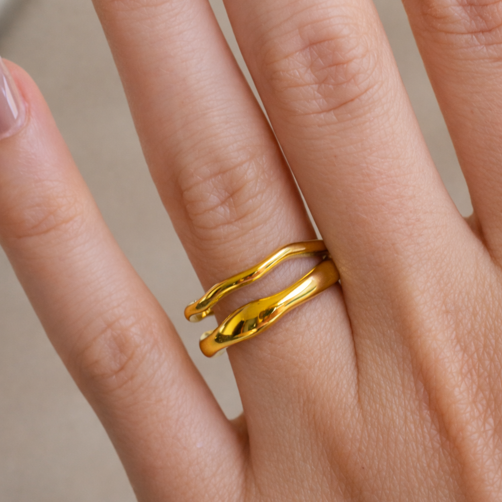 Gold ring on a person's finger against a neutral background