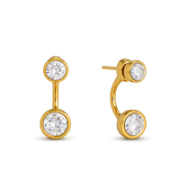 A pair of gold hoop earrings with round bezel-set clear gemstones, shown on a plain white background. One earring is oriented vertically, and the other is angled to show the post and backing.