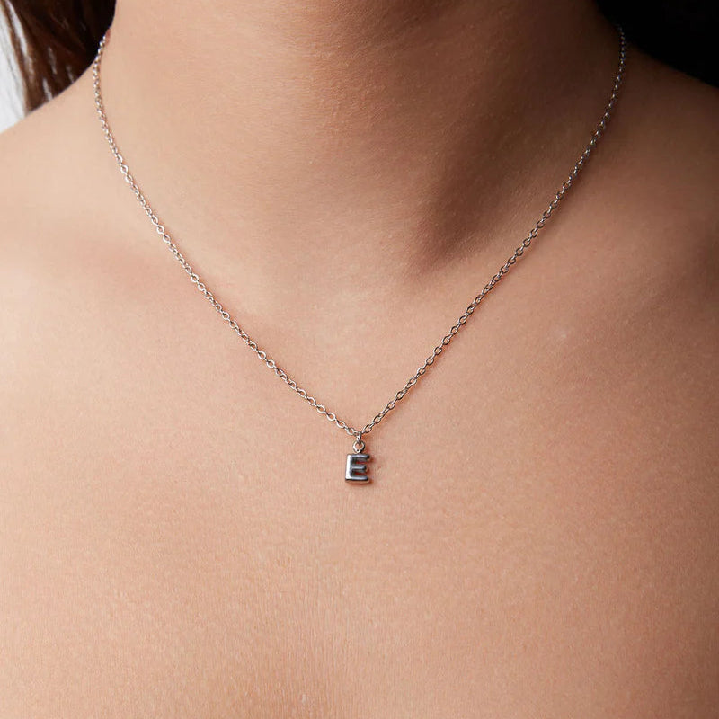 Necklace with a small pendant on a person's neck against a neutral background