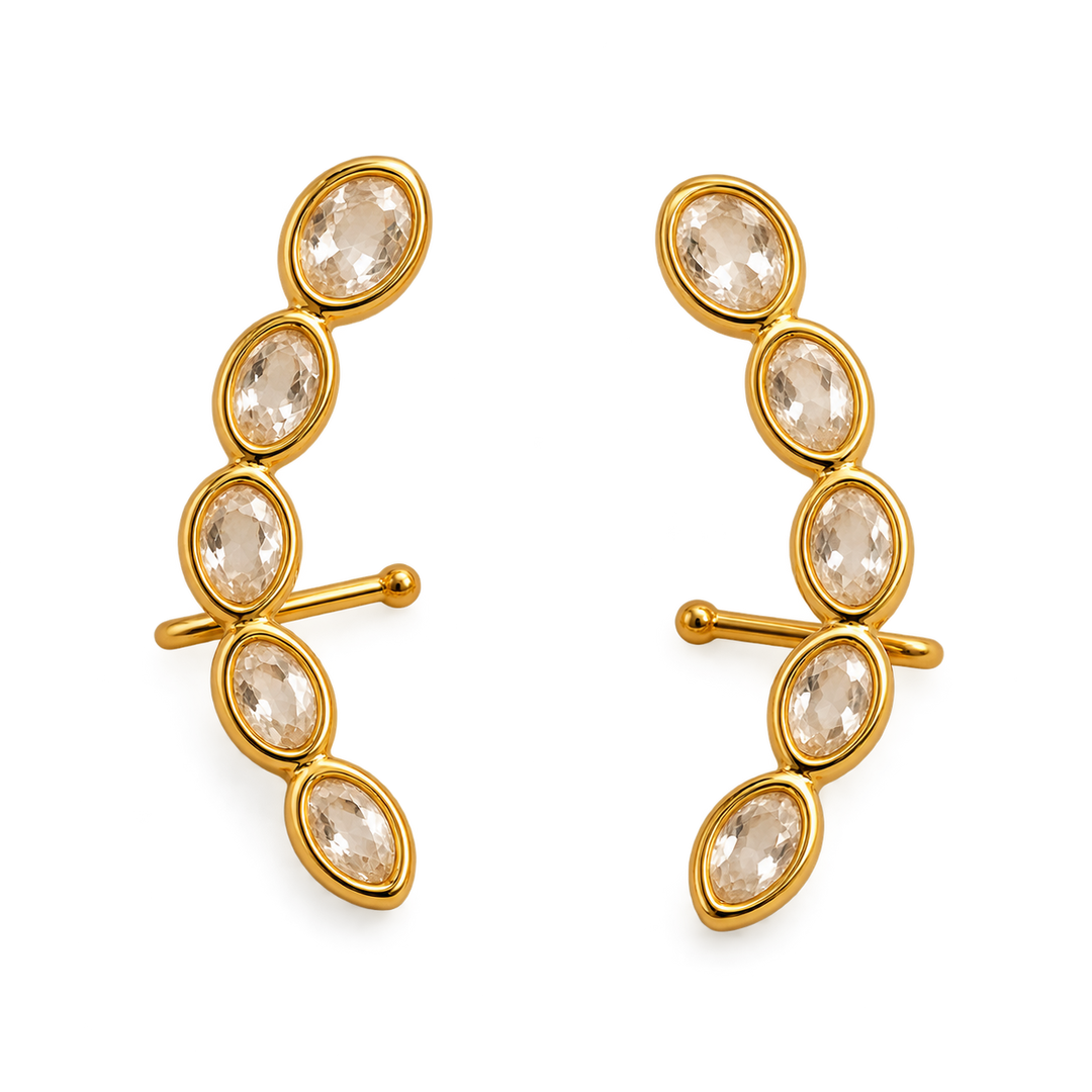 A pair of gold crescent-shaped clip-in earrings, each adorned with five marquise-cut clear crystals in a curved row, set against a plain white background.