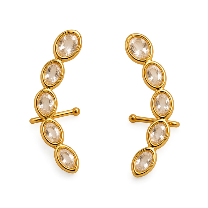 A pair of gold crescent-shaped clip-in earrings, each adorned with five marquise-cut clear crystals in a curved row, set against a plain white background.