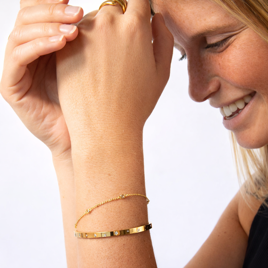 Woman wearing a gold bracelet on a plain background
