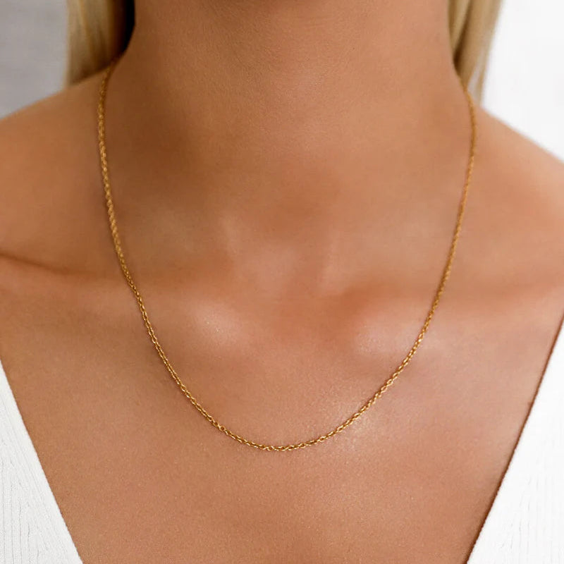 Gold necklace on a model with a plain background