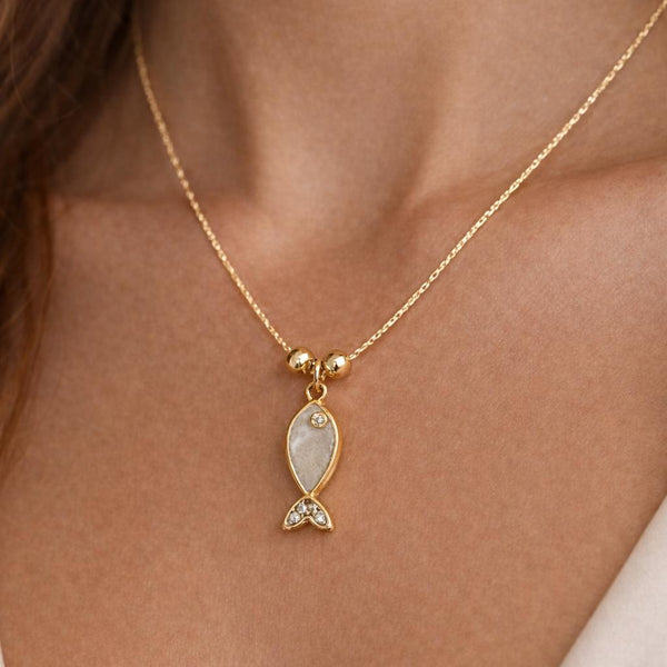 Gold necklace with a fish-shaped pendant on a person's neck
