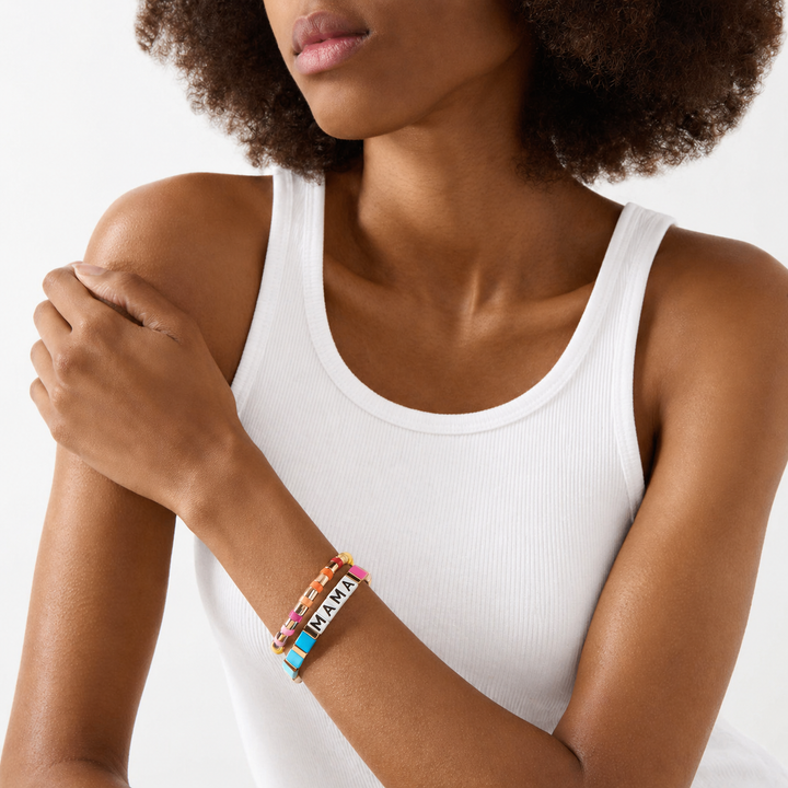 Woman wearing a white tank top with colorful bracelets on a plain background