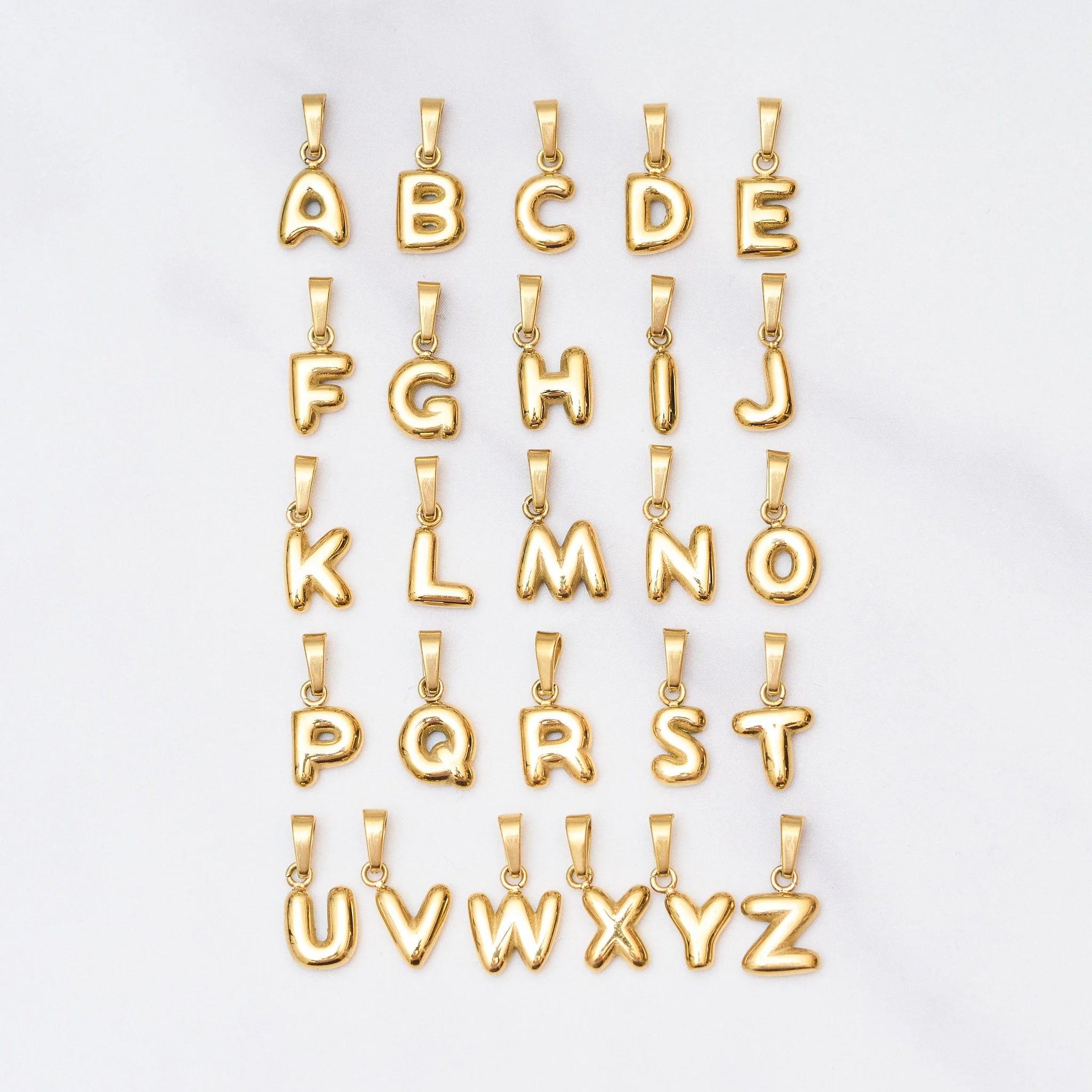 Gold letter pendants from A to Z on a white background