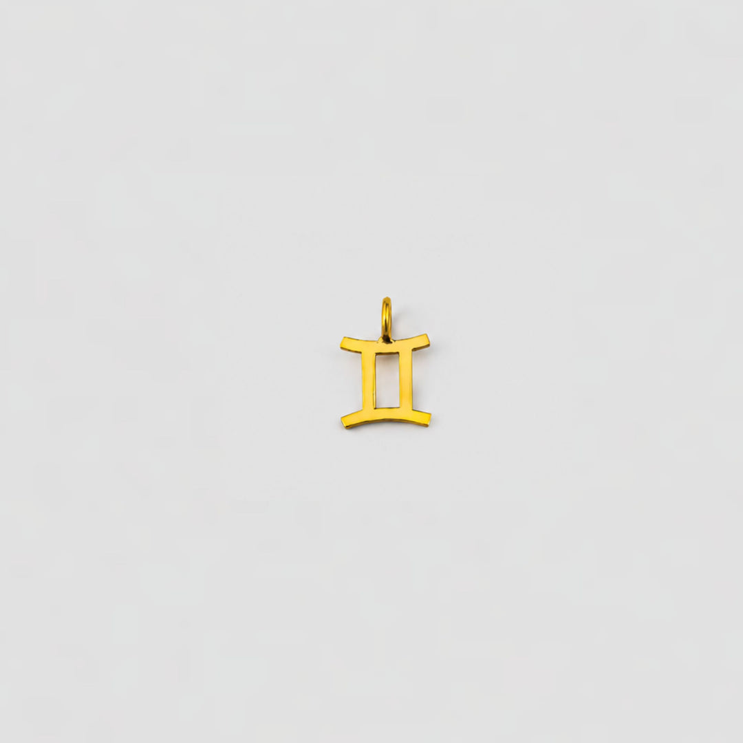 Gold Gemini zodiac pendant on a light gray background