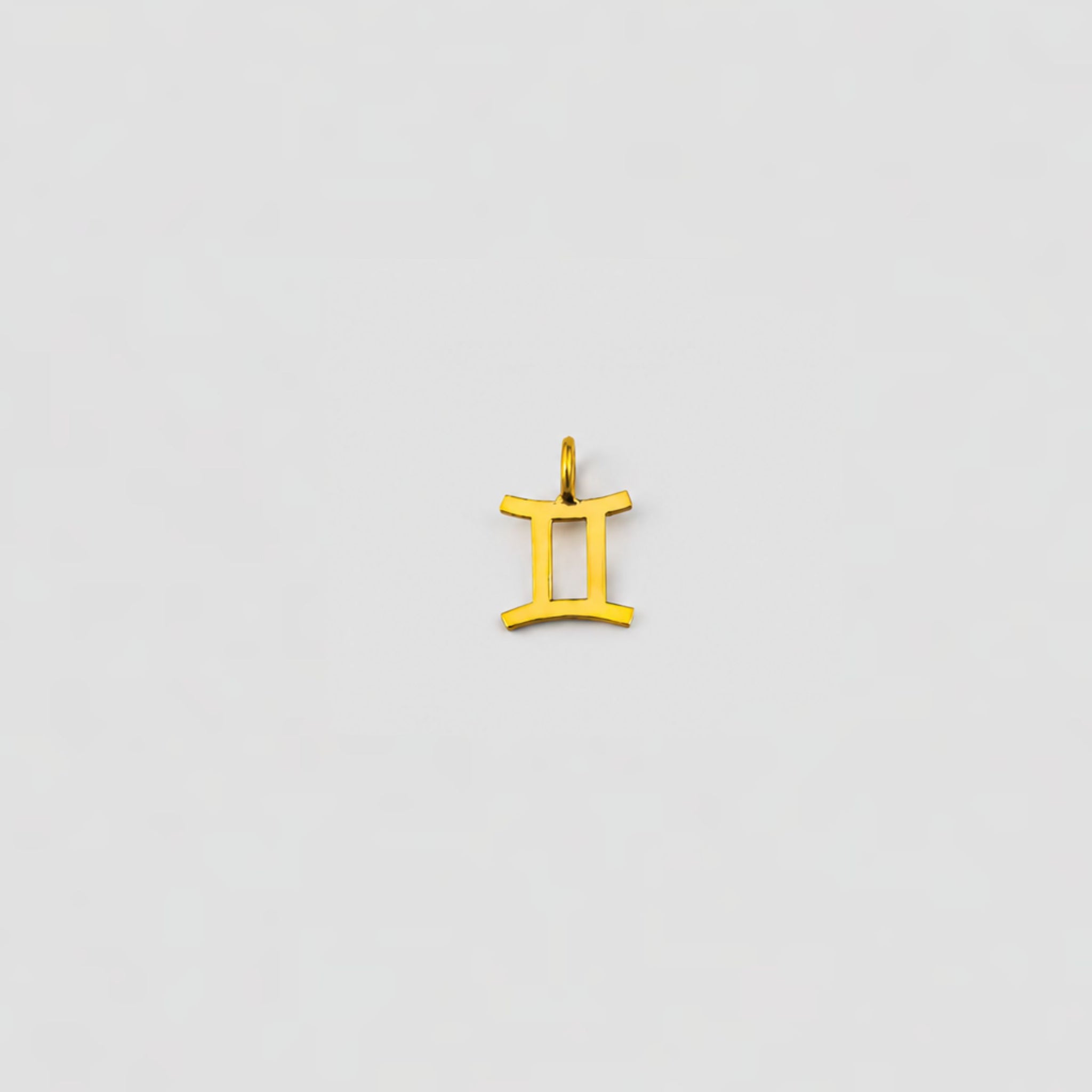 Gold Gemini zodiac pendant on a light gray background
