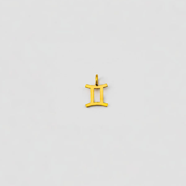 Gold Gemini zodiac pendant on a light gray background