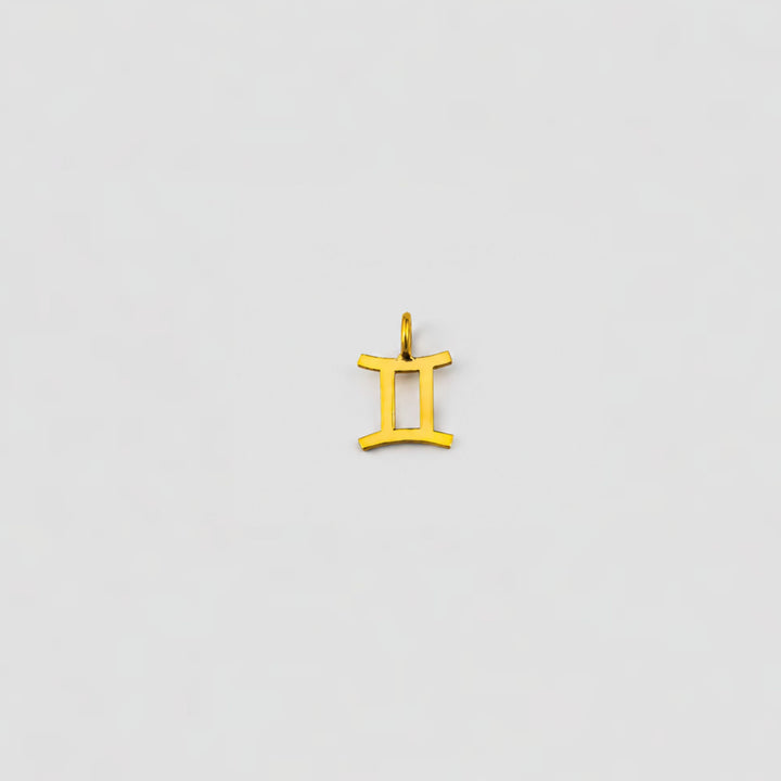 Gold Gemini zodiac pendant on a light gray background