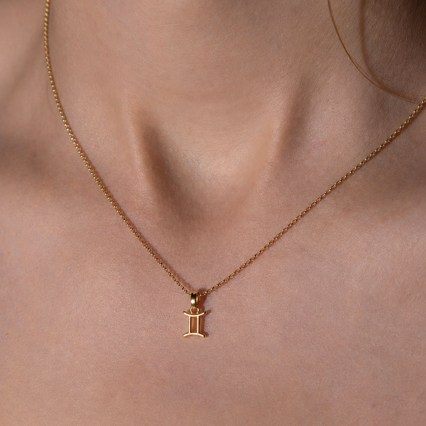 Gold necklace with a pendant on a person's neck