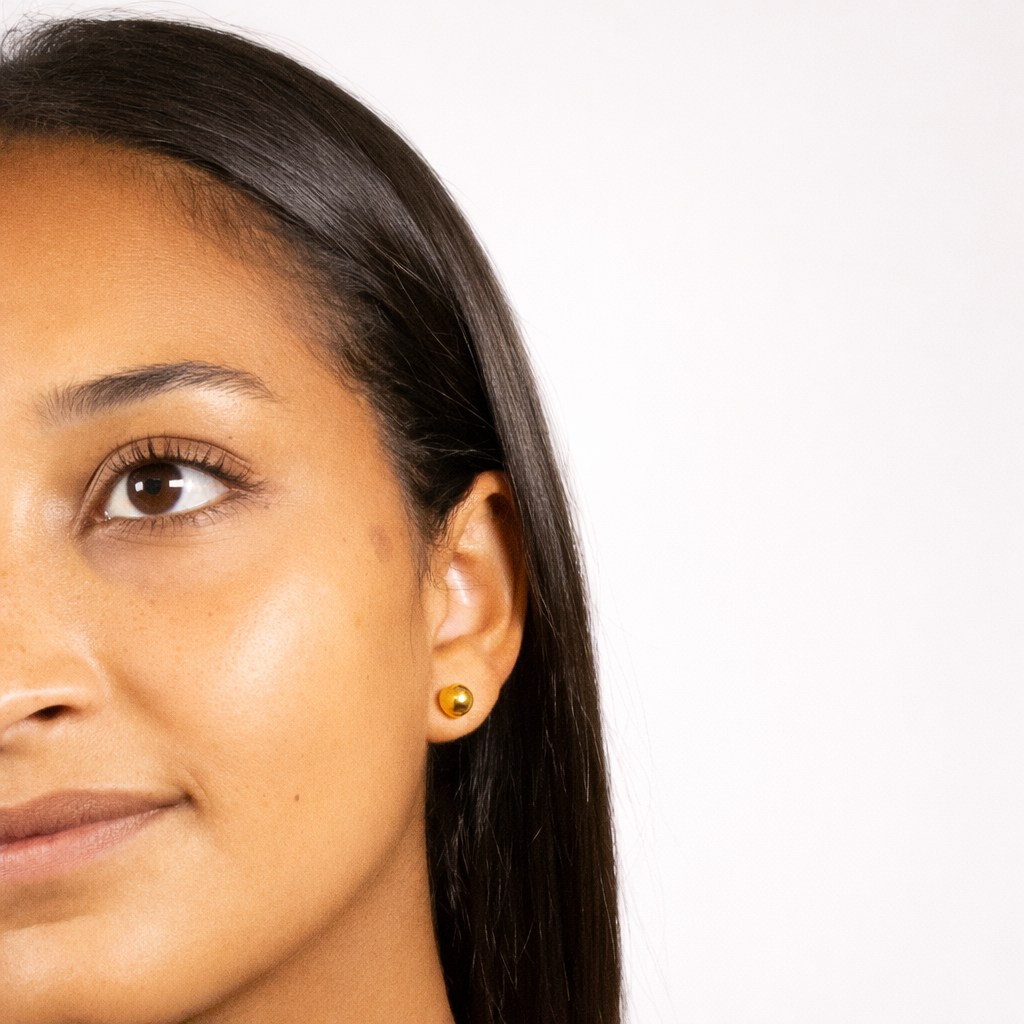 Close-up of a woman's face with a gold earring on a white background