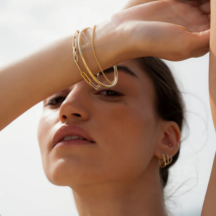 Woman wearing gold jewelry with a blurred background