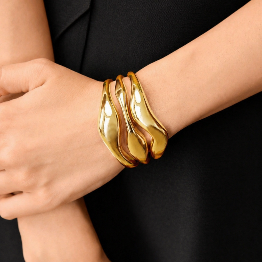 Gold bracelet on a person's wrist against a black background