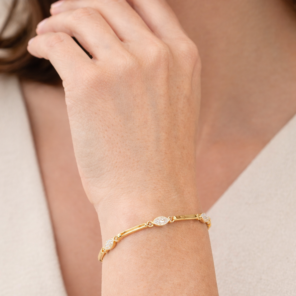 Gold bracelet with small stones on a person's wrist against a neutral background