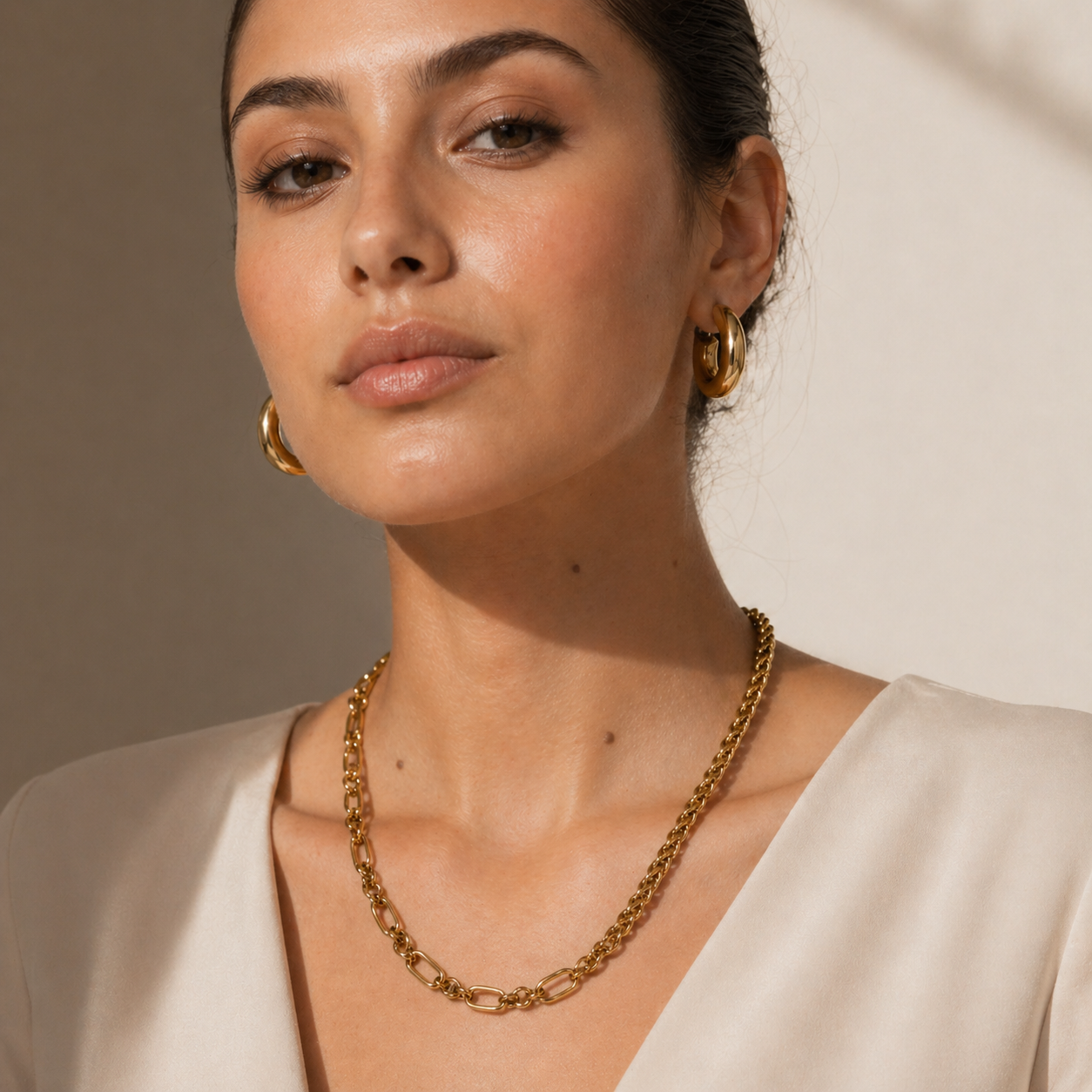 Woman wearing gold jewelry against a neutral background