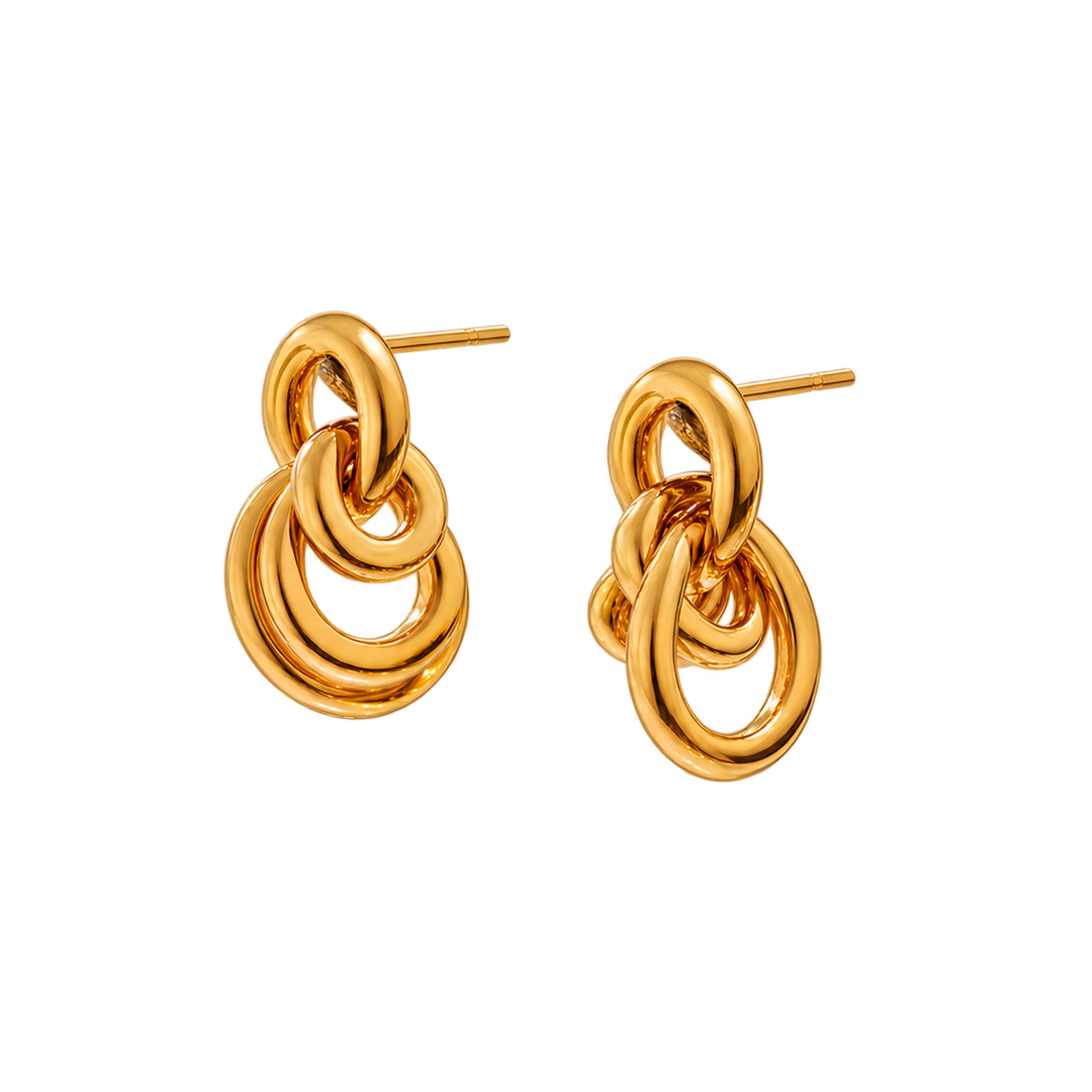 A pair of gold-toned dangle earrings with a layered, interlocking ring design and flat post backings, shown on a plain white background.