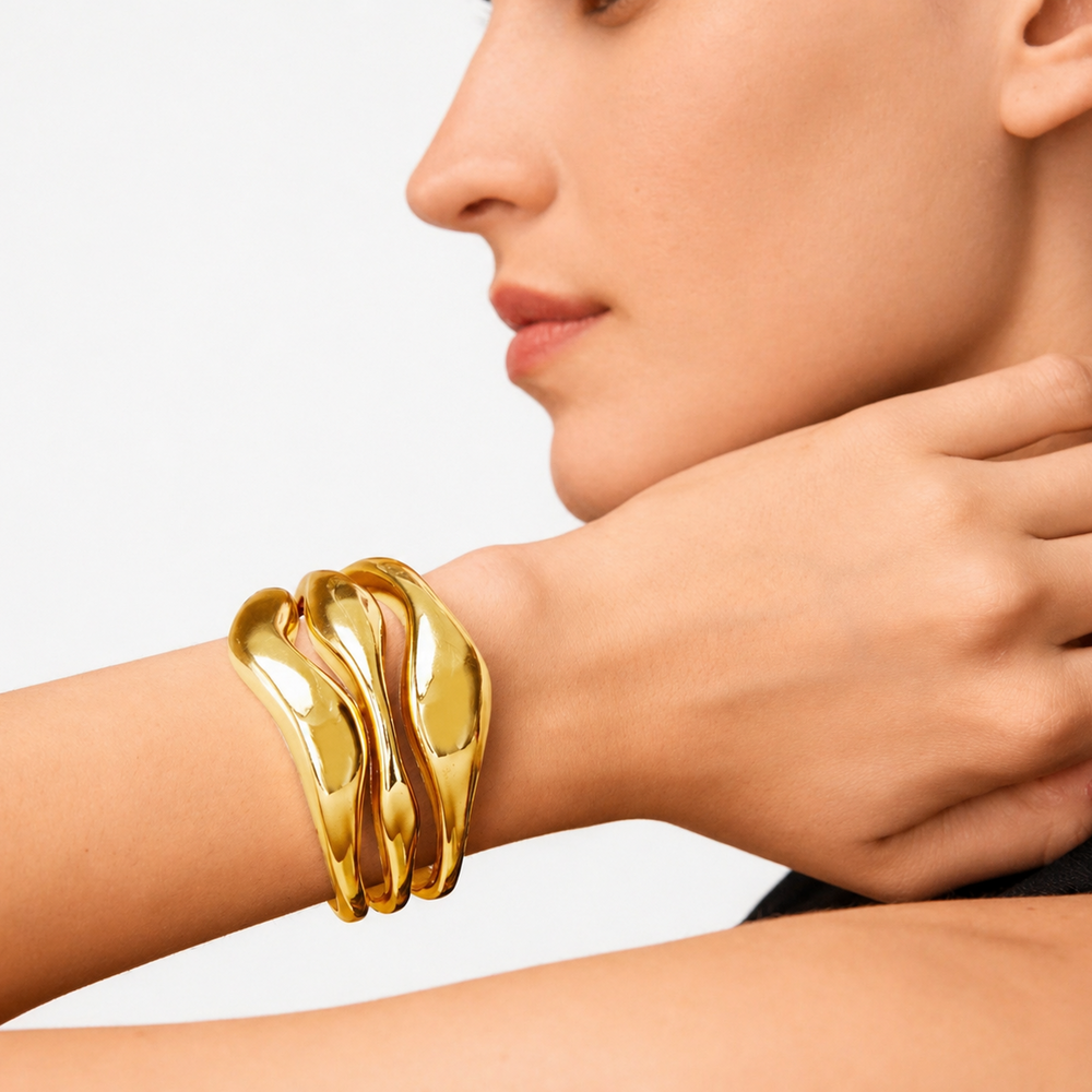 Gold bracelet on a wrist with a neutral background