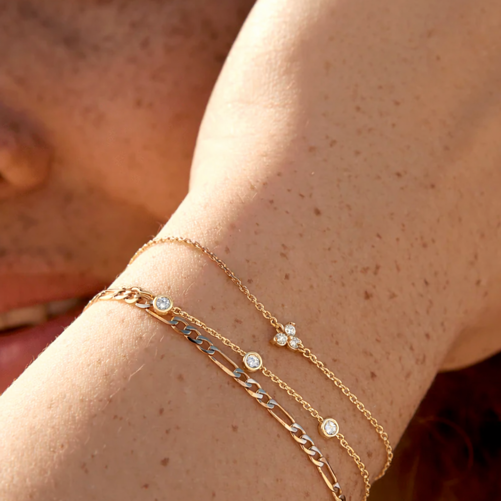 Close-up of a person's wrist wearing multiple gold bracelets with small stones.