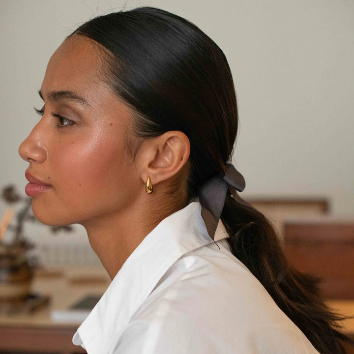 Woman with a ponytail wearing a white shirt in an indoor setting
