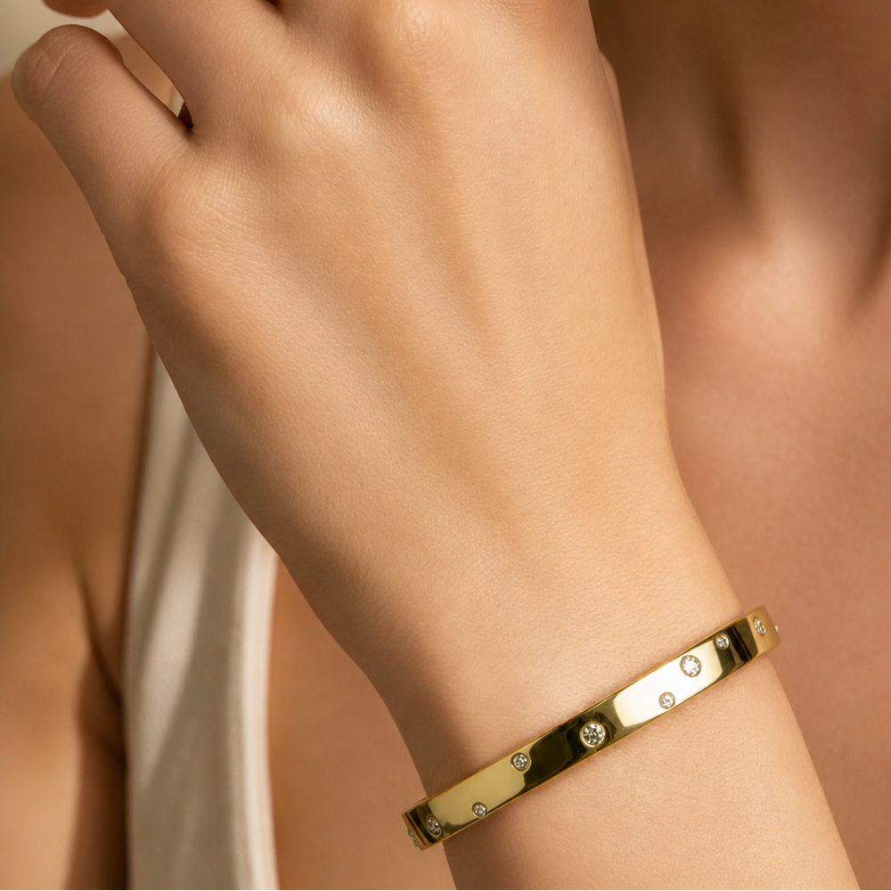 Gold bracelet on a wrist with a neutral background