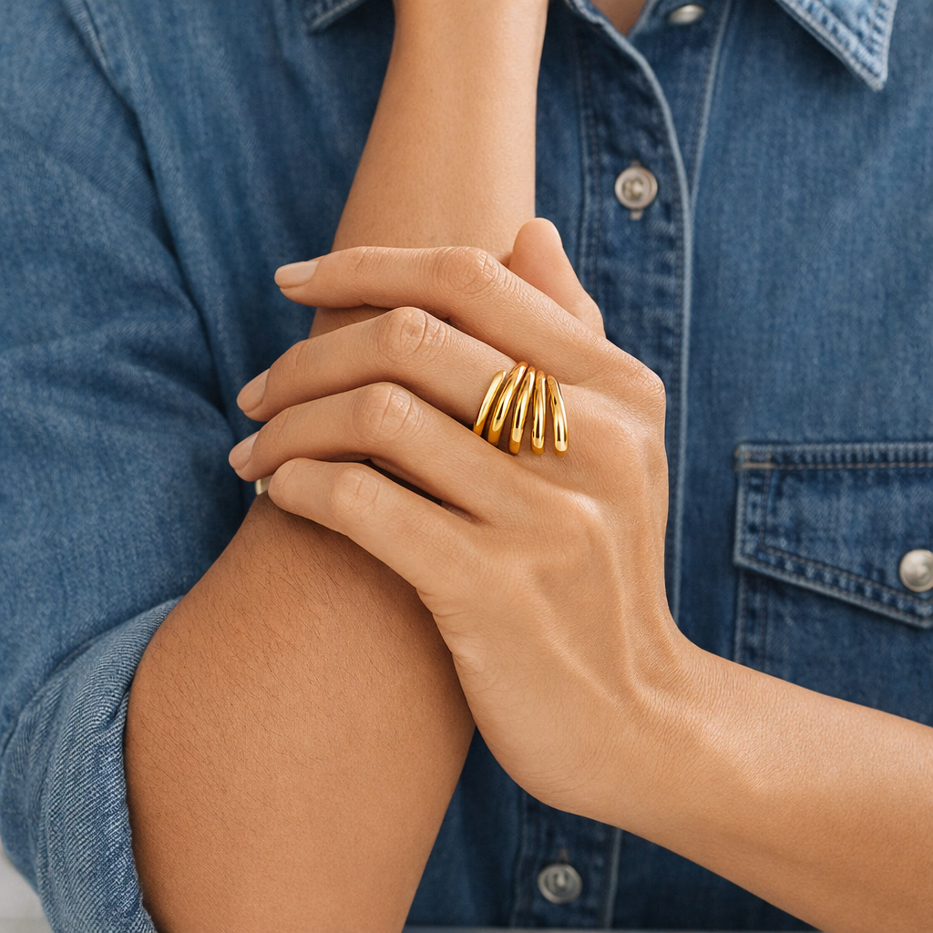 Close-up of a hand wearing gold rings with a denim background