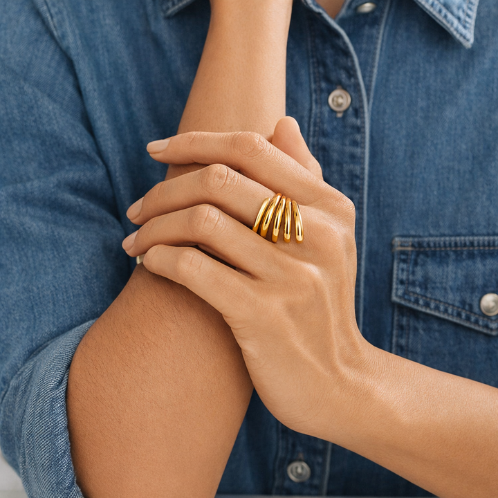 Close-up of a hand wearing gold rings with a denim background