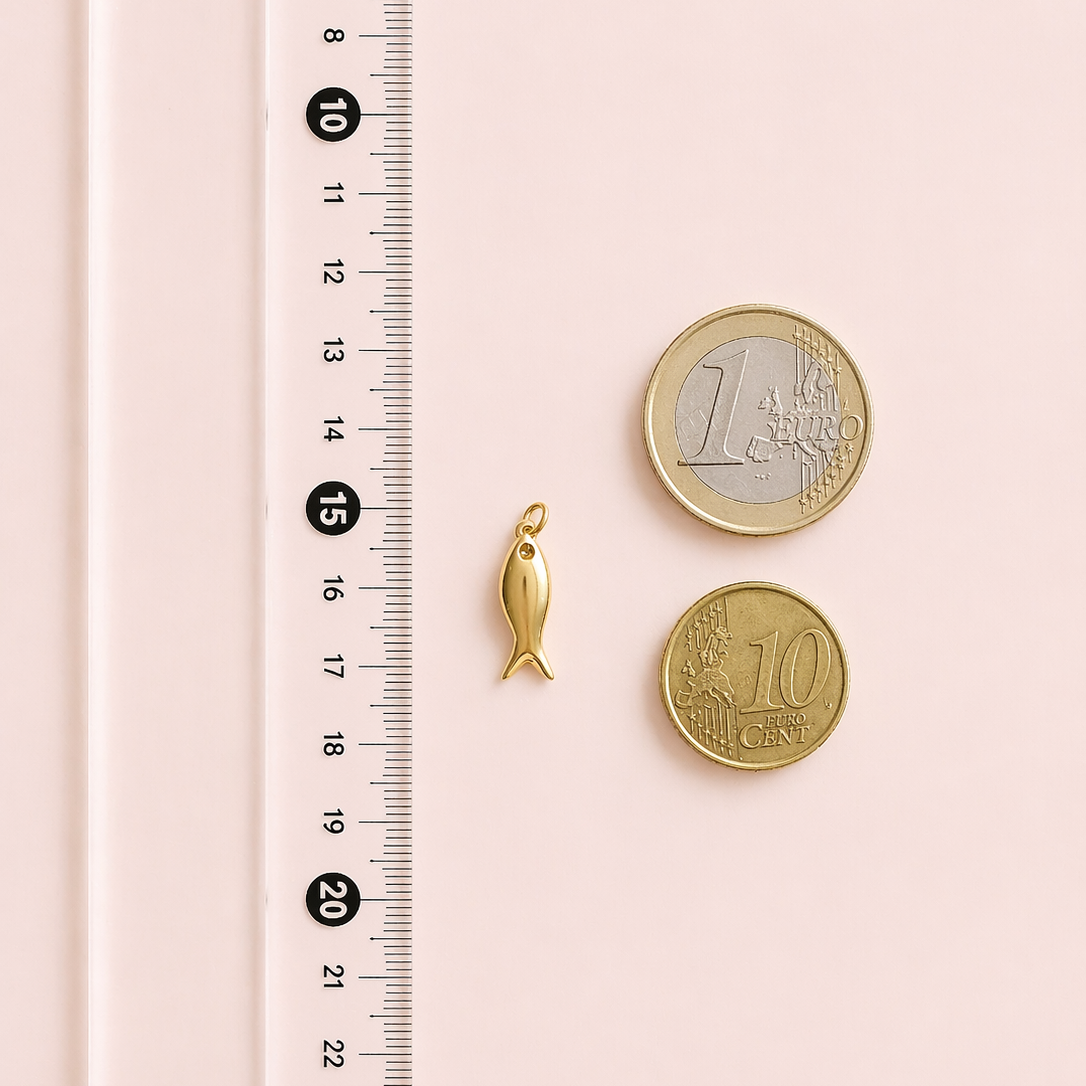 Gold fish charm and two coins next to a ruler on a pink background