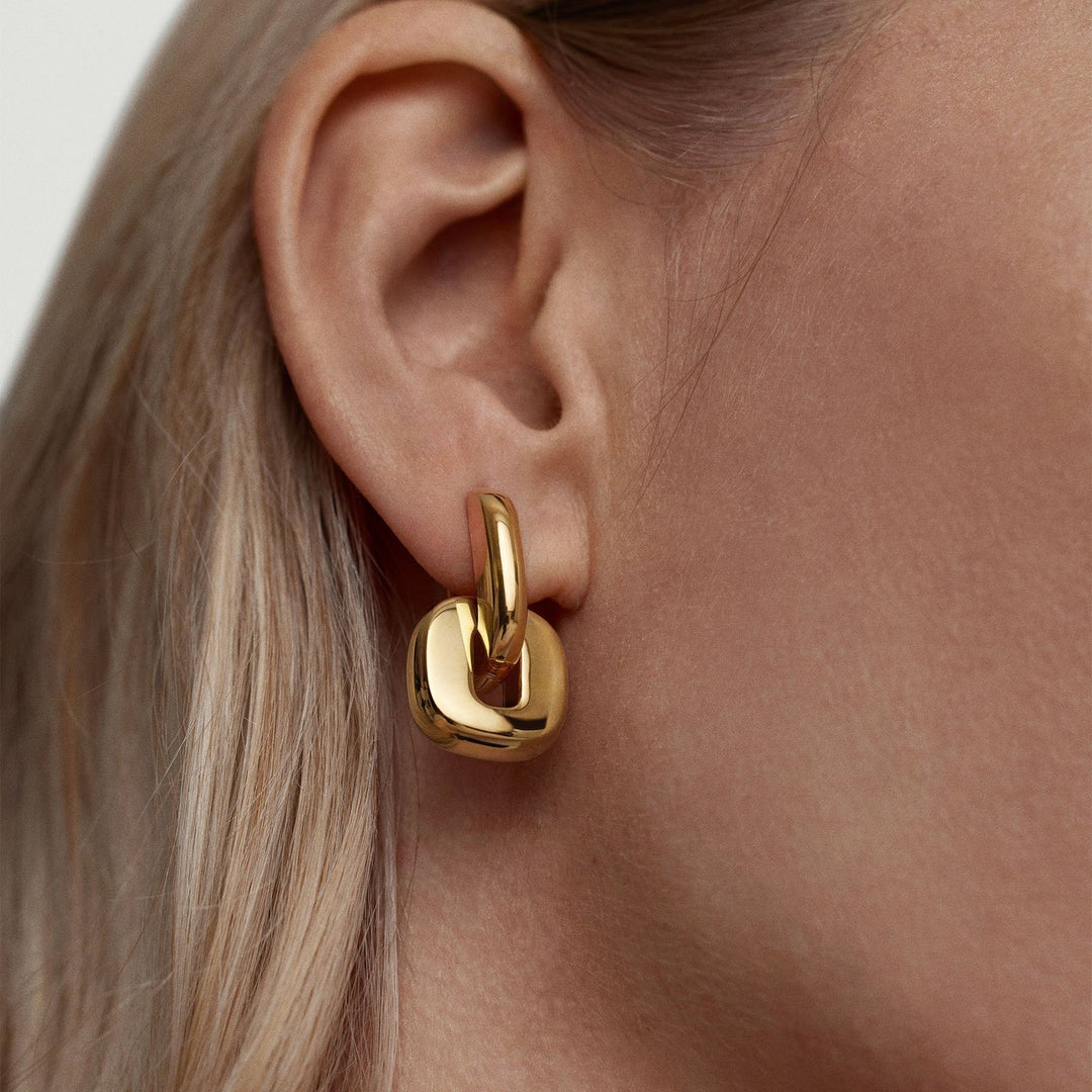 Gold hoop earring worn by a person with blonde hair.