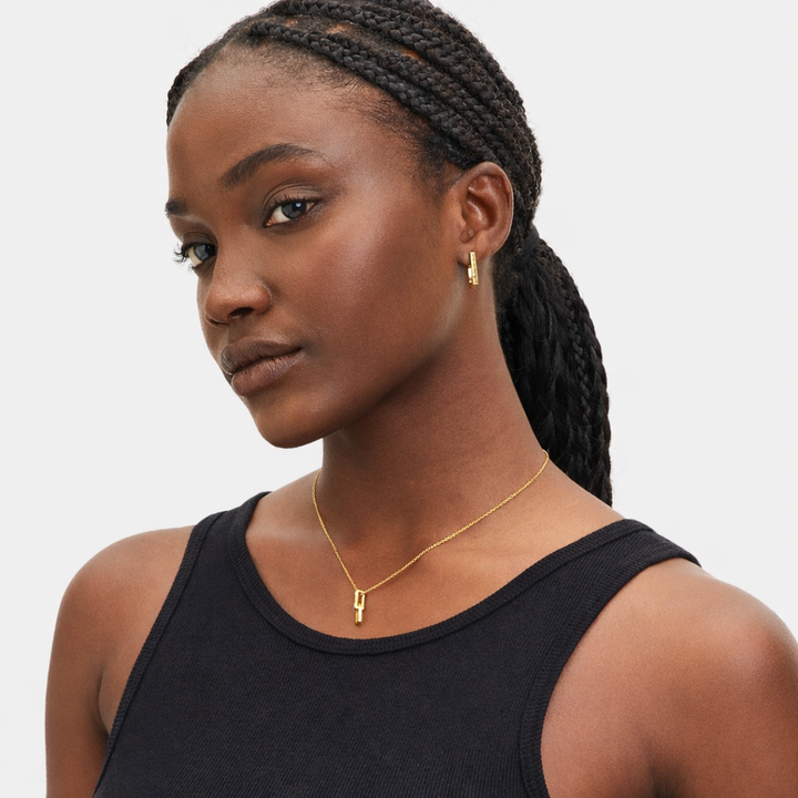 Woman wearing a black top and gold necklace with a neutral background
