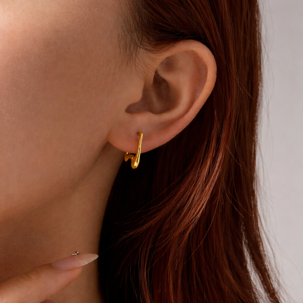 Close-up of a person wearing a gold hoop earring with a neutral background
