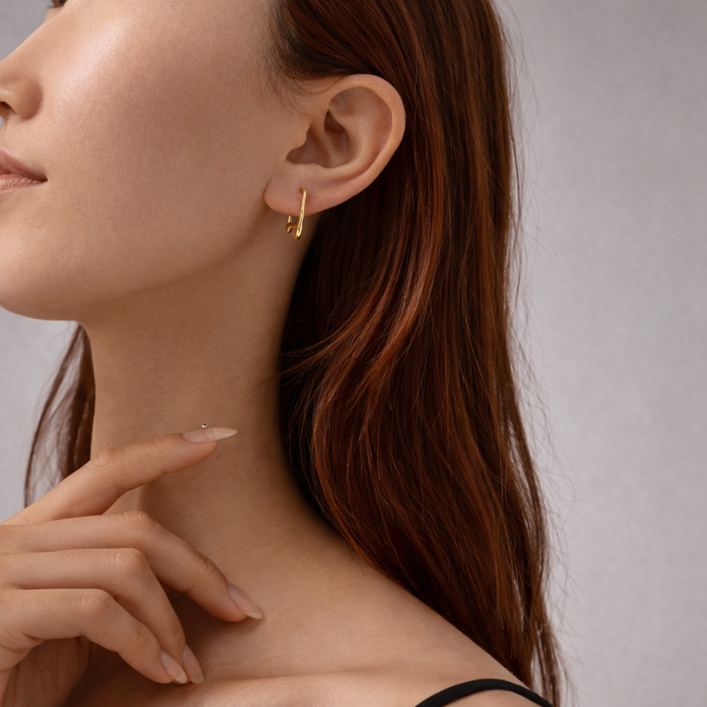 Close-up of a woman wearing gold earrings with a neutral background