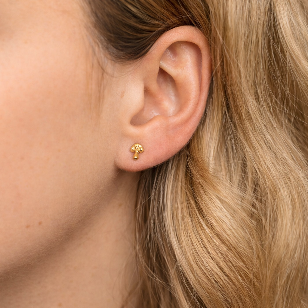 Close-up of an ear wearing a gold earring with blonde hair.