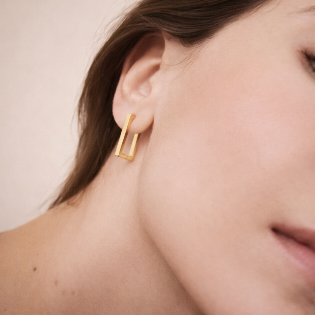 Gold hoop earring worn by a person with a neutral background