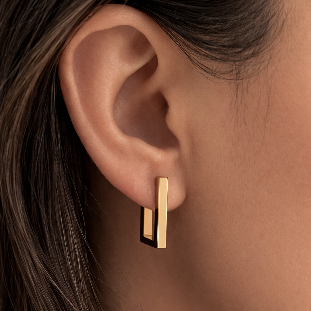 Gold hoop earrings worn by a person with dark hair.