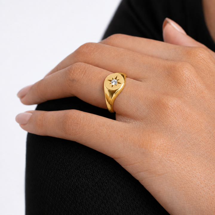 Silver ring with a diamond on a person's finger against a white background