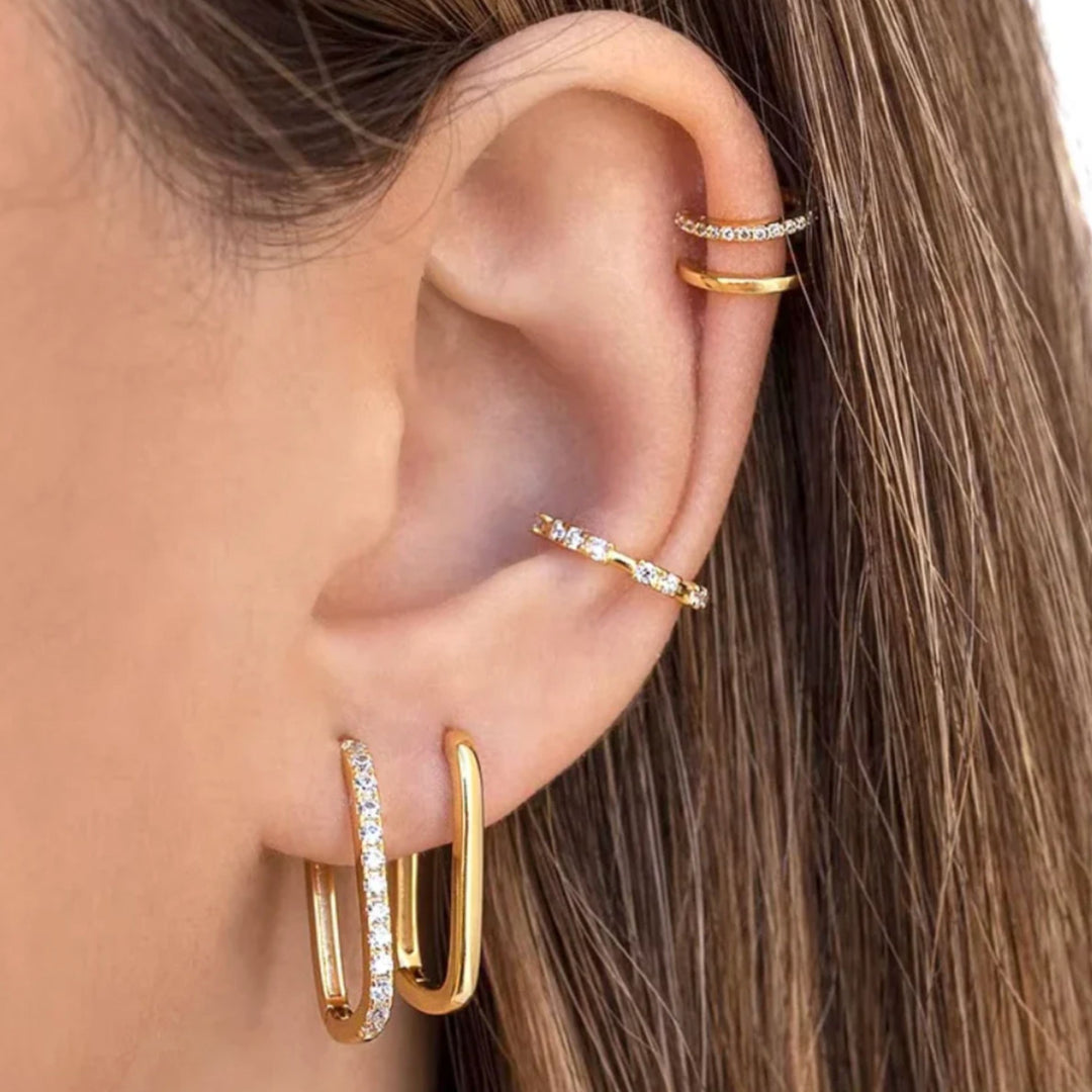 Close-up of an ear wearing gold hoop earrings and a gold ear cuff.