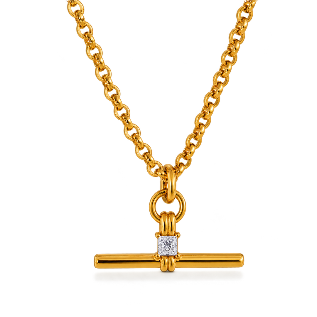 A gold chain necklace with a bar pendant featuring a square clear gemstone, shown on a clean white background.