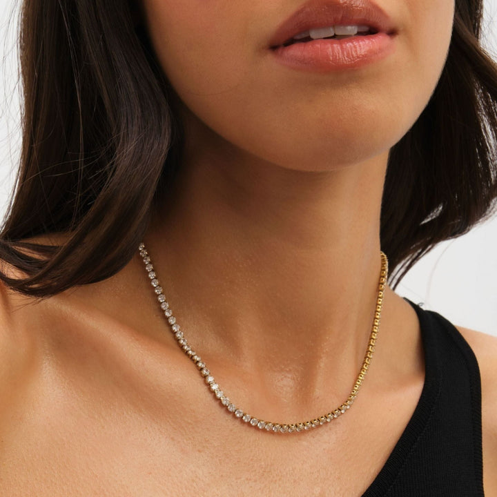 Close-up of a woman wearing a gold necklace with a plain background