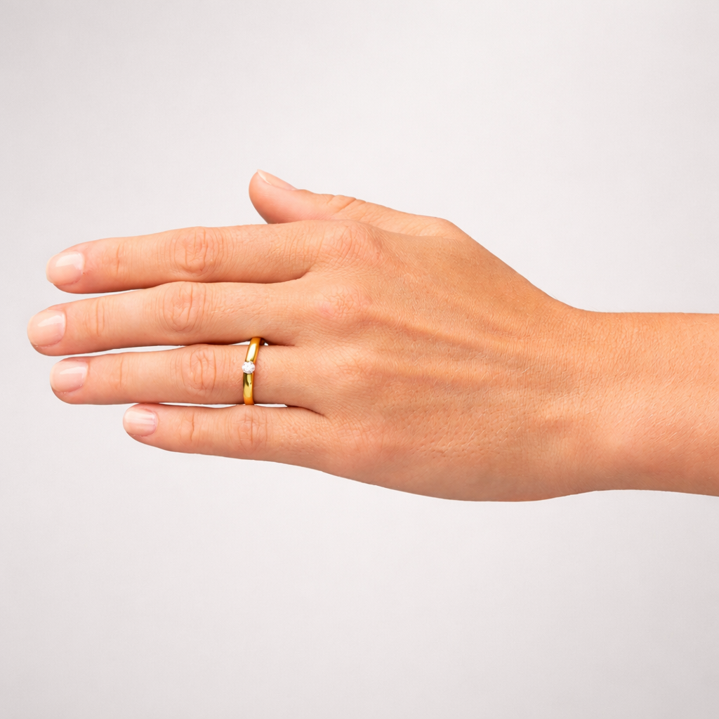 Hand wearing two rings on a plain background
