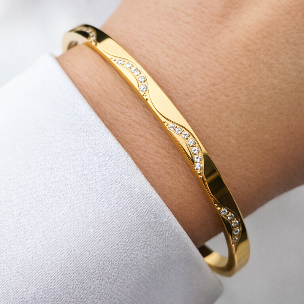 Gold bracelet with small diamonds on a wrist against a white background