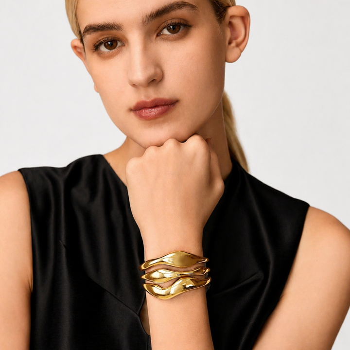 Woman wearing a gold bracelet on a plain background