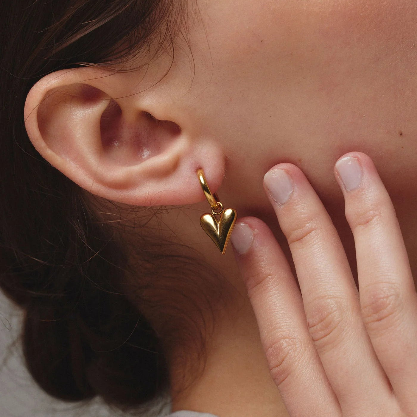 Close-up of a person wearing a gold heart-shaped earring.