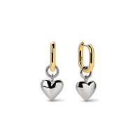 A pair of gold and silver dangle earrings on a clean white background. Each earring features a polished silver heart charm suspended from a gold huggie hoop.