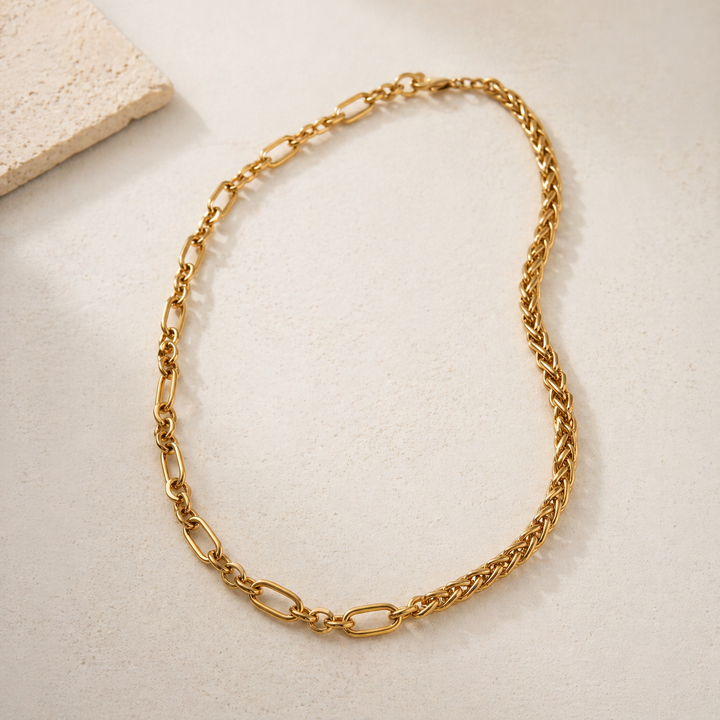 Gold chain necklace on a light beige surface