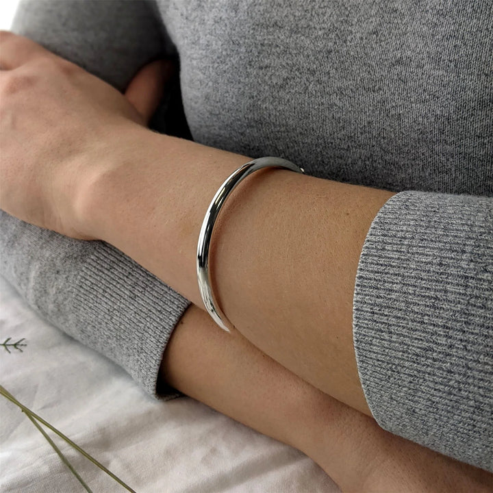 Silver bracelet on a person's wrist with a gray sleeve