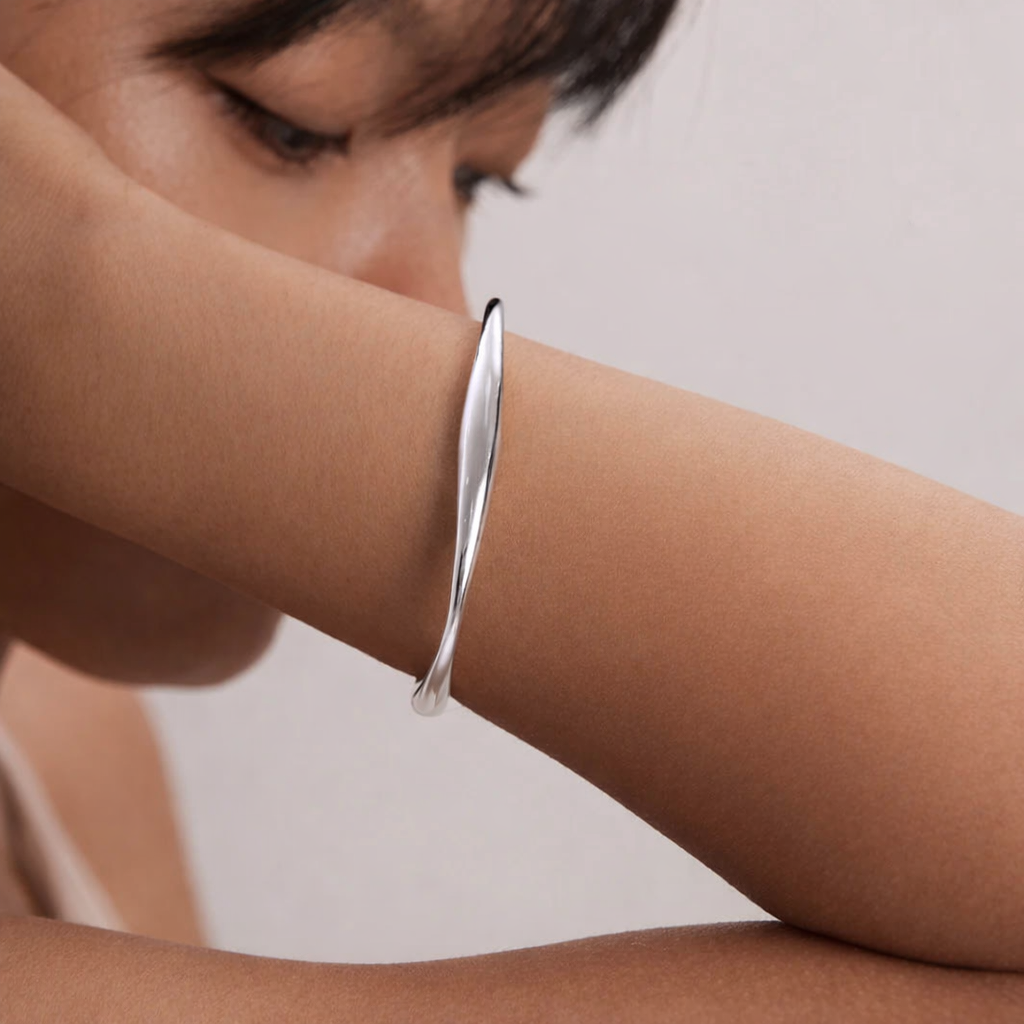 Silver bracelet on a person's wrist against a neutral background