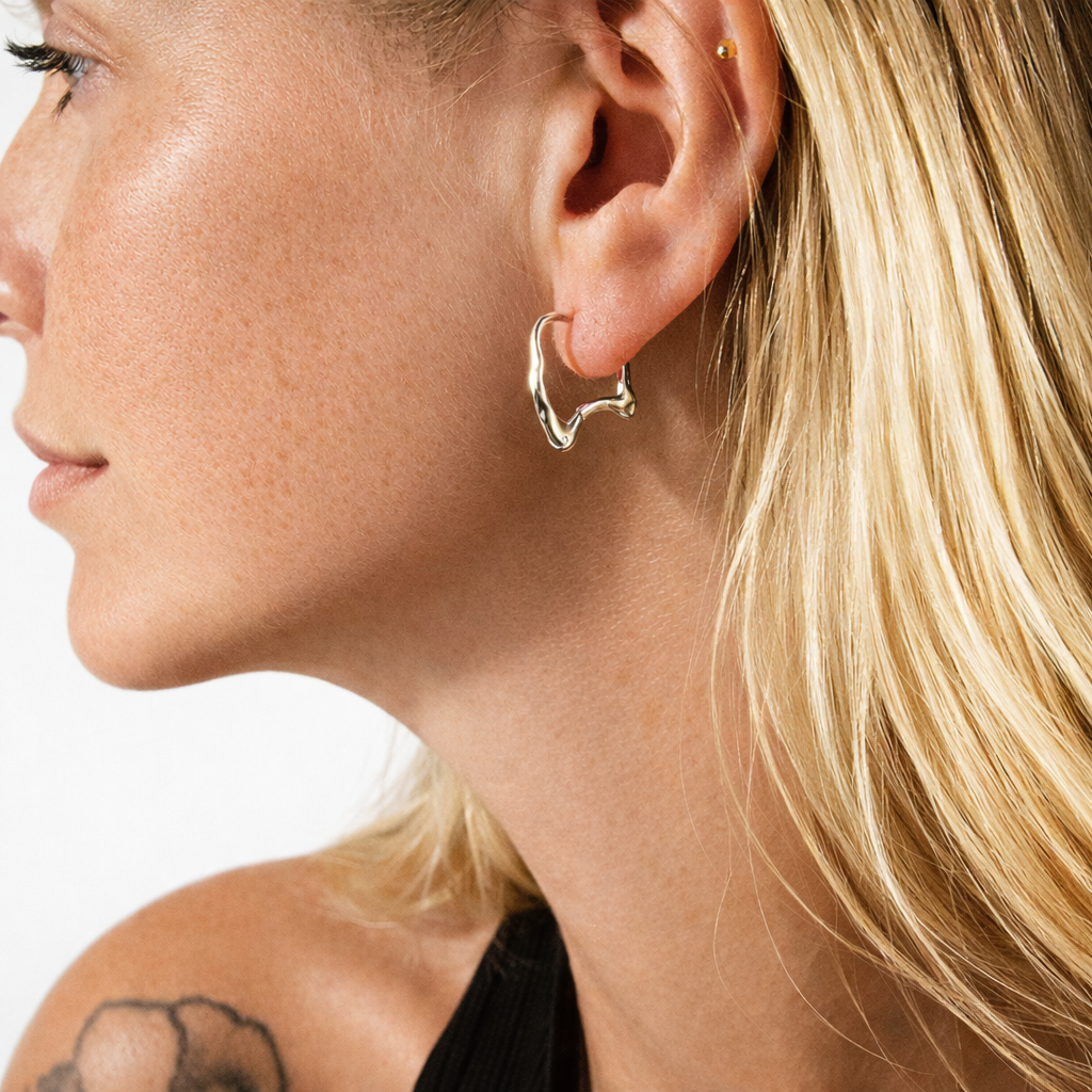 Close-up of a woman wearing a gold hoop earring on a white background